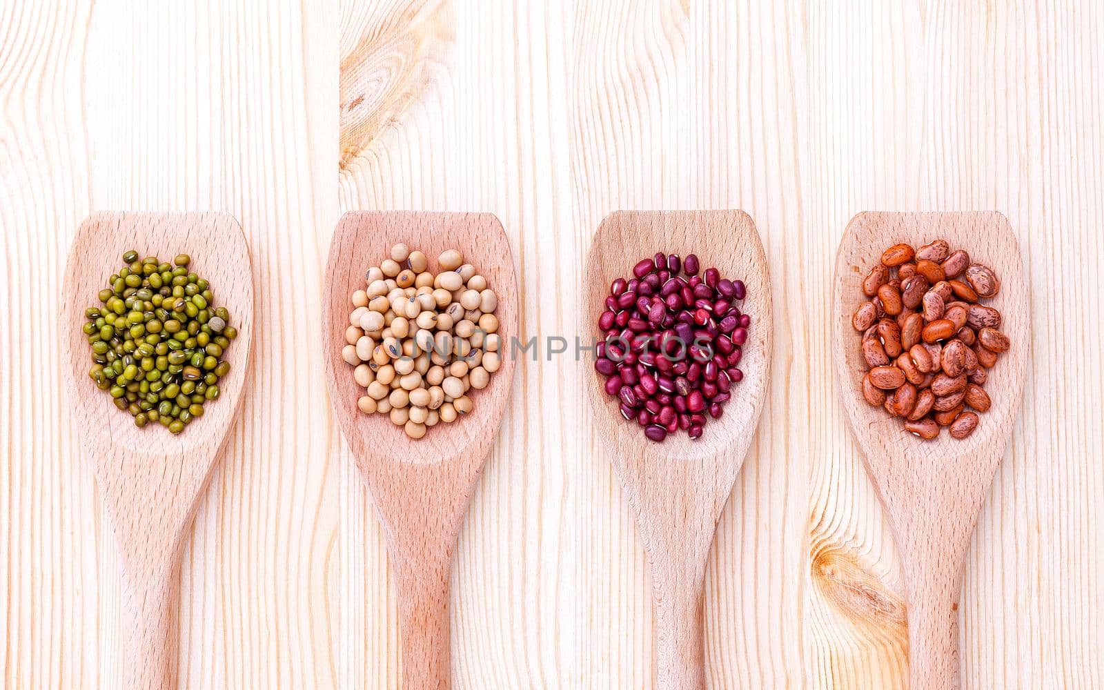 Assortment of beans and lentils in wooden spoon on wooden background.  soybean, mung bean , red bean and brown pinto beans .