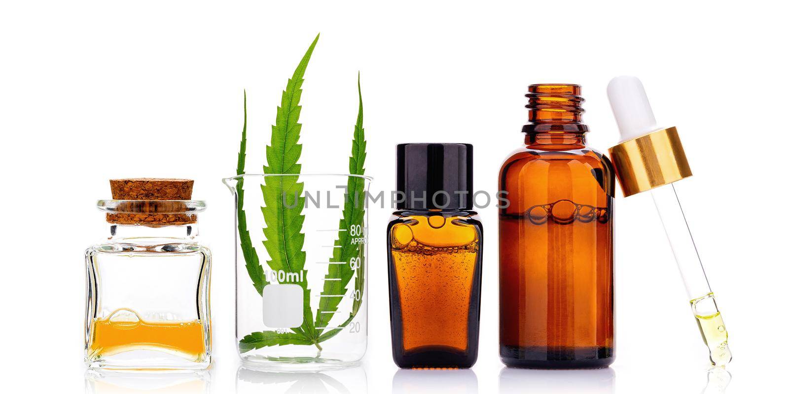 Glass bottles of cannabis oil and hemp leaves isolated on white background.
