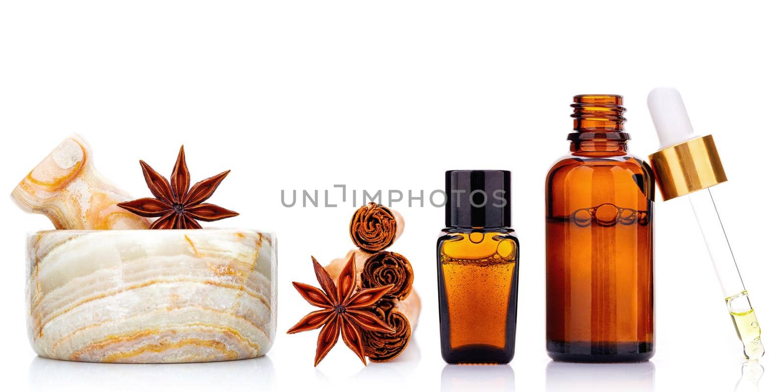Cinnamon essential oil bottle with Ceylon cinnamon sticks and anise star isolated on white background .
