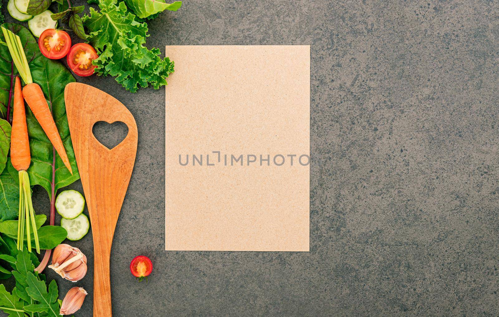 Wooden Spatula and vegetables on dark stone background. Healthy food and cooking concept.