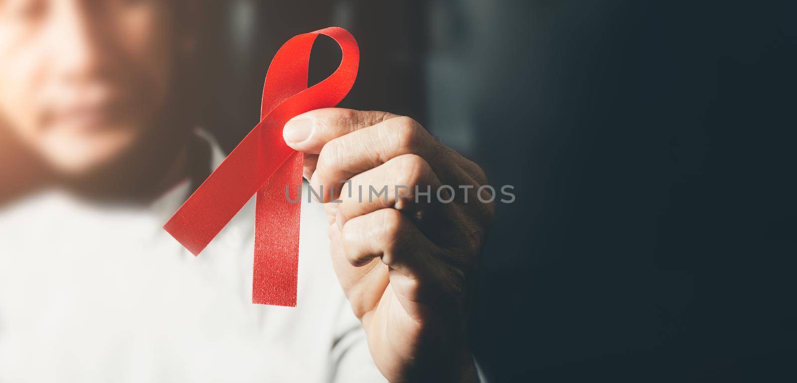 World AIDS day awareness ribbon,Female hands holding red ribbon HIV,Healthcare and medicine concept.