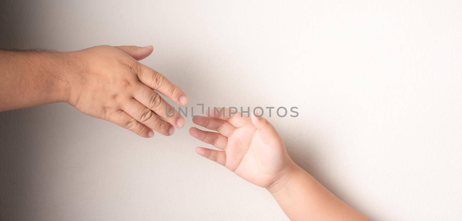 Father's hand to hold the hand of a child with Down's syndrome