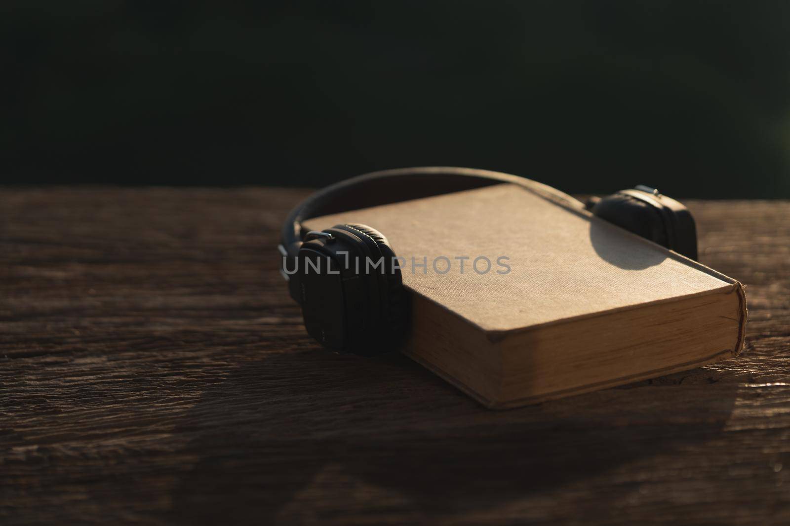Audio book concept. Headphones and old book on wood