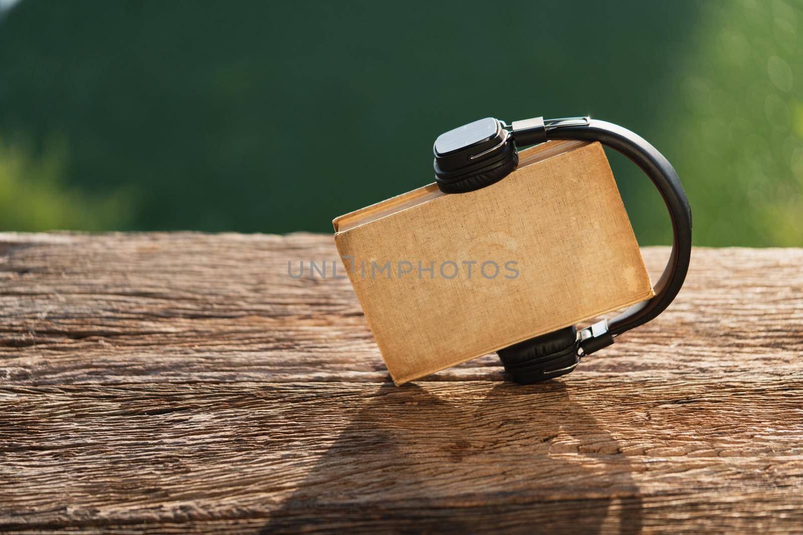 Audio book concept. Headphones and old book on wood