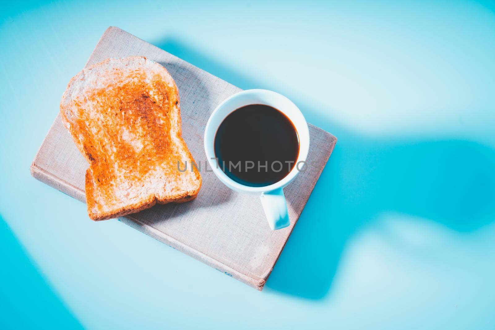 Toast slice with coffee cup on book, Bread grill, top view