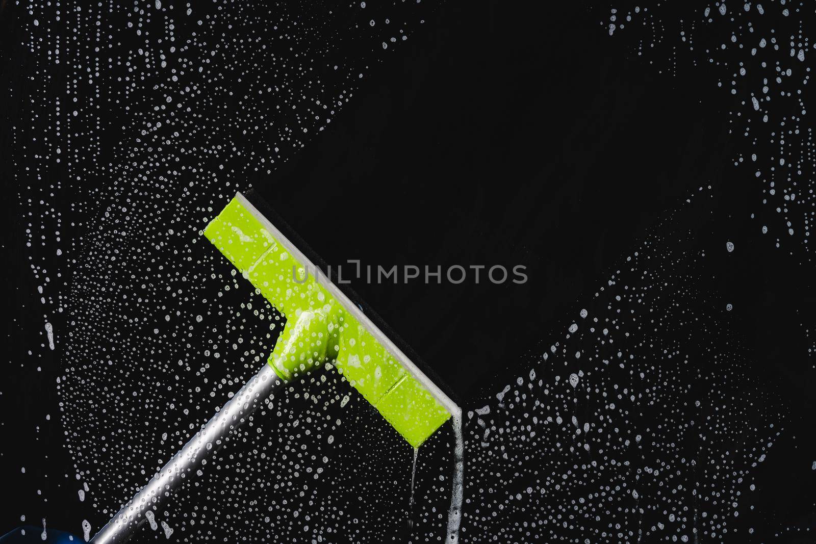 Glass cleaner using a squeegee to wash a window.