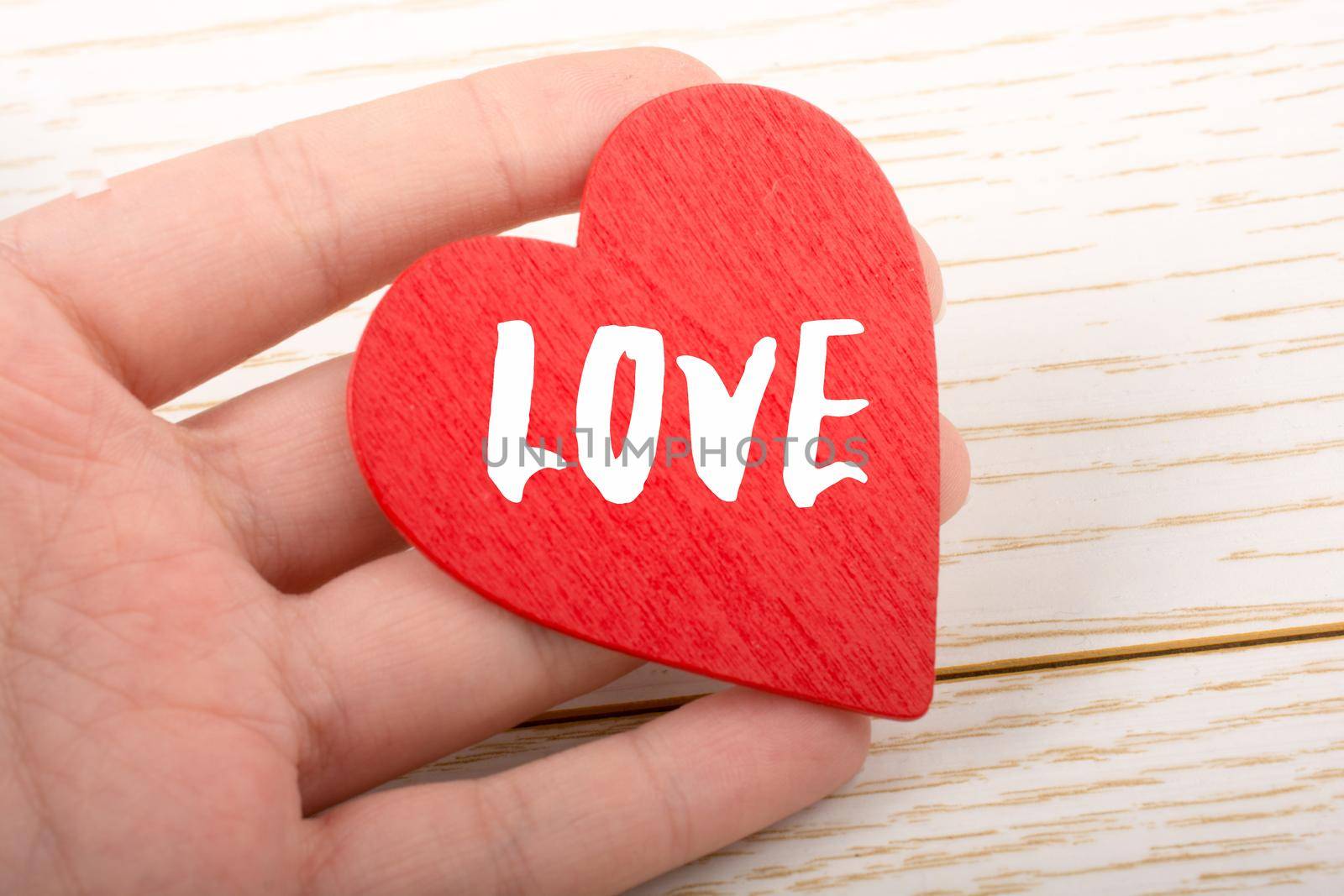 Red color heart shaped object in hand with LOVE wording by berkay