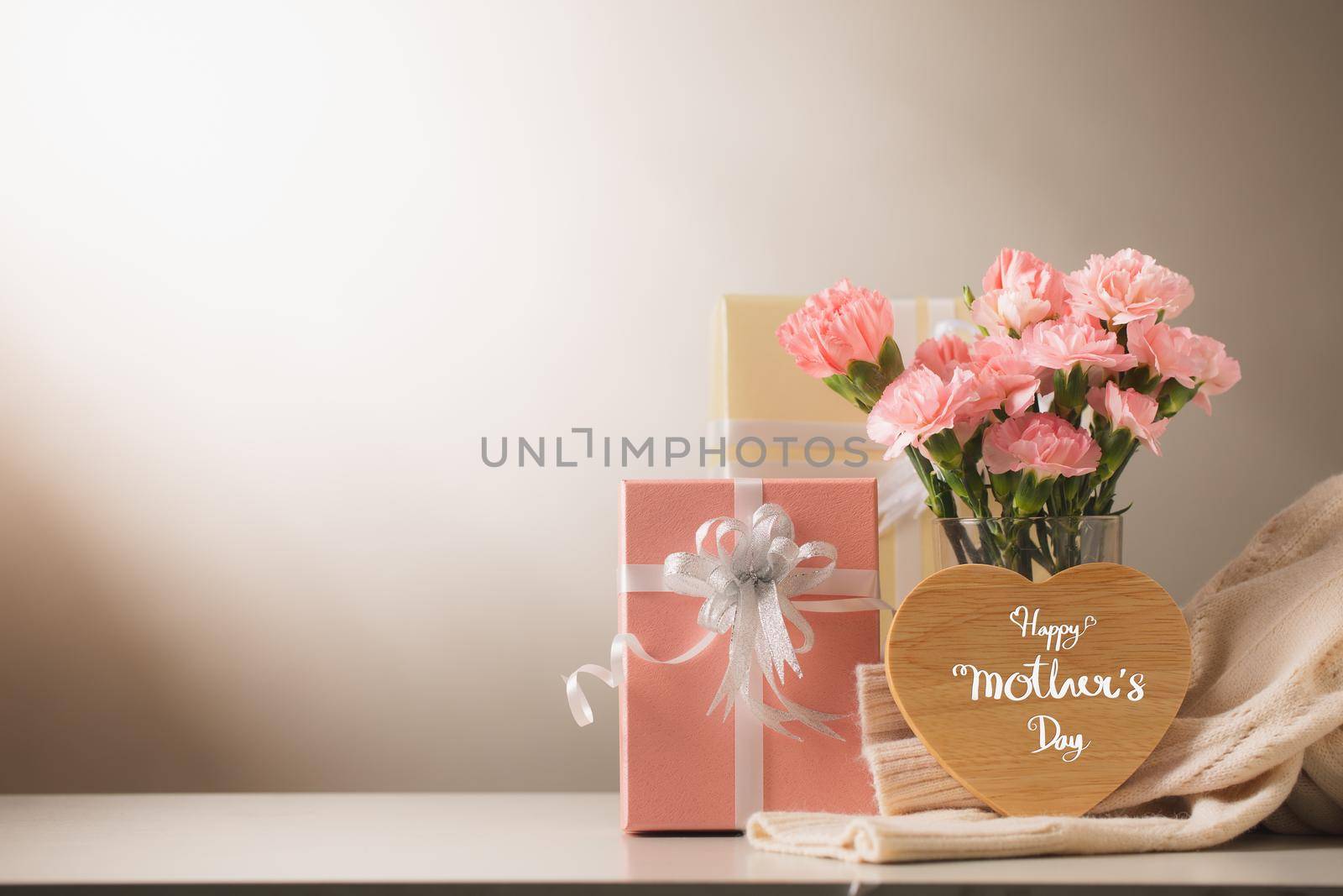 Still life with sweet carnation flowers and gift on table, Mothers day concept