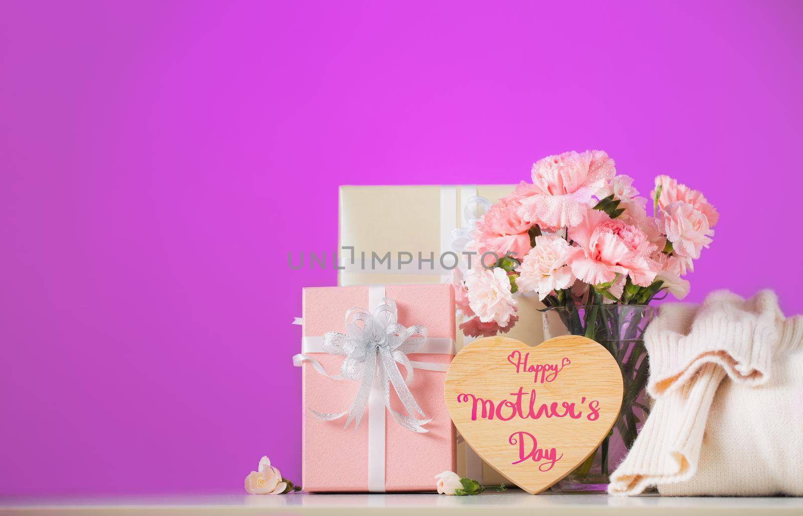 Still life with sweet carnation flowers and gift on table, Mothers day concept