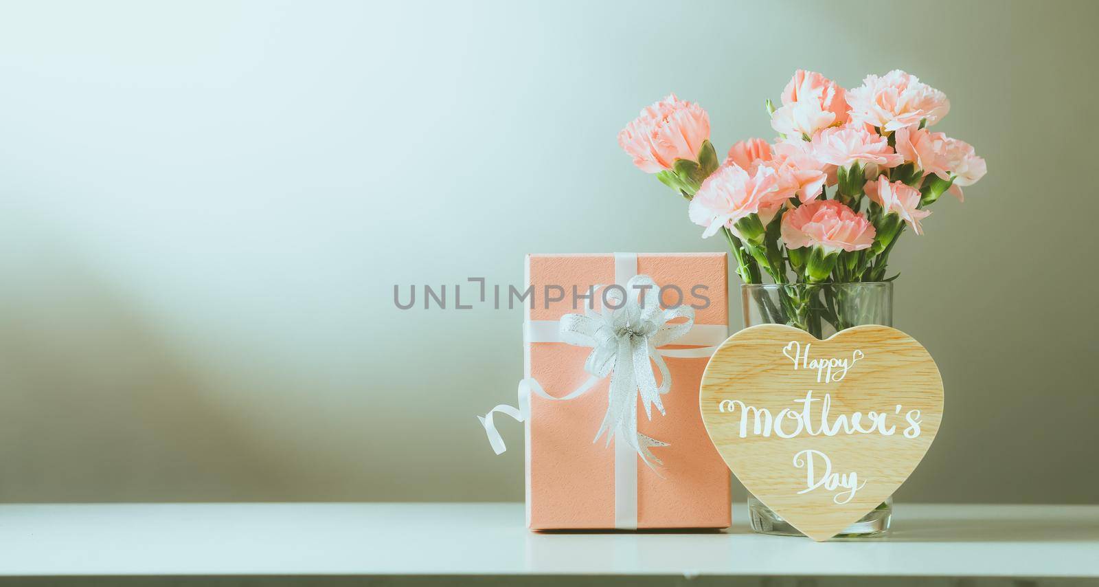 Still life with sweet carnation flowers and gift on table, Mothers day concept, Vintage filter color