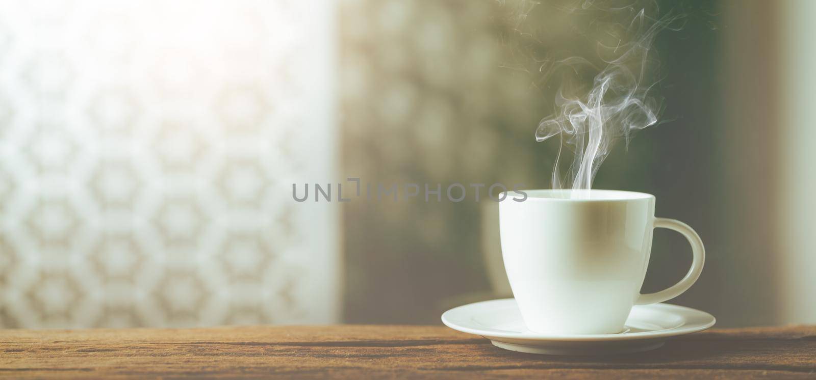 White cup of coffee on wooden beside wondow