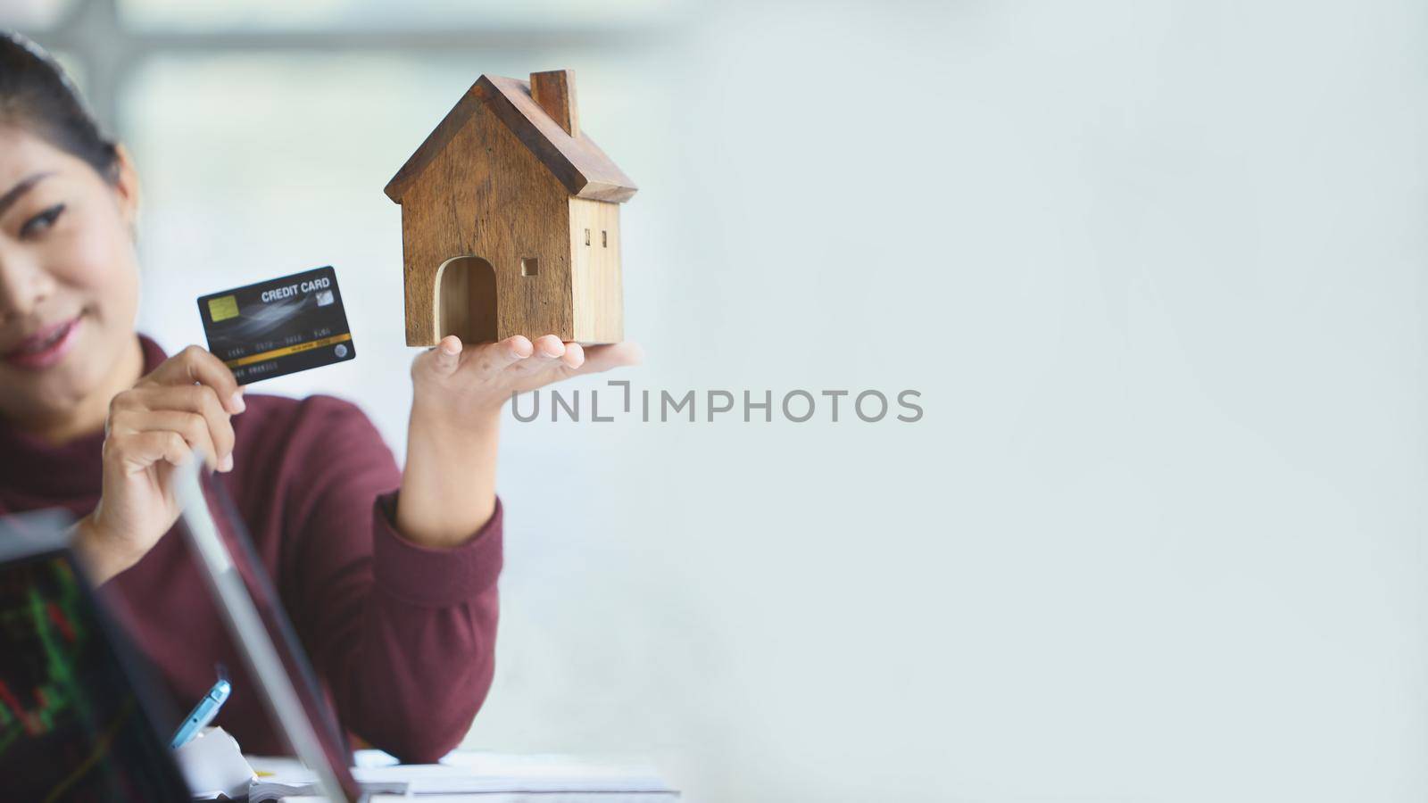 Hand of woman holding a toy house with copy space. Filing a home on credit