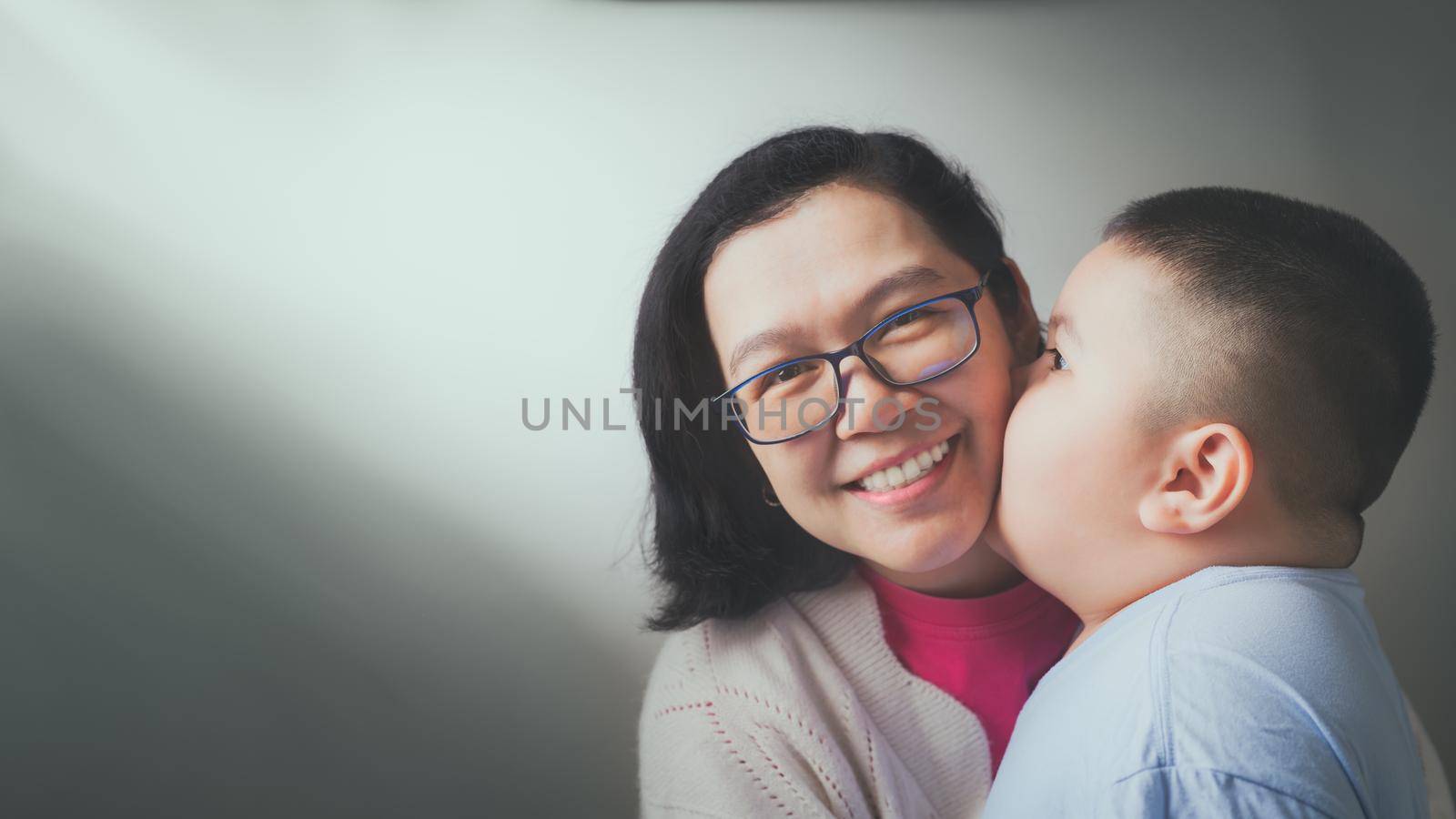 Happy Mother's Day! The son of the child congratulates her mother and kisses her cheek. Mother and boy smile and hug Family holidays and cohabitation