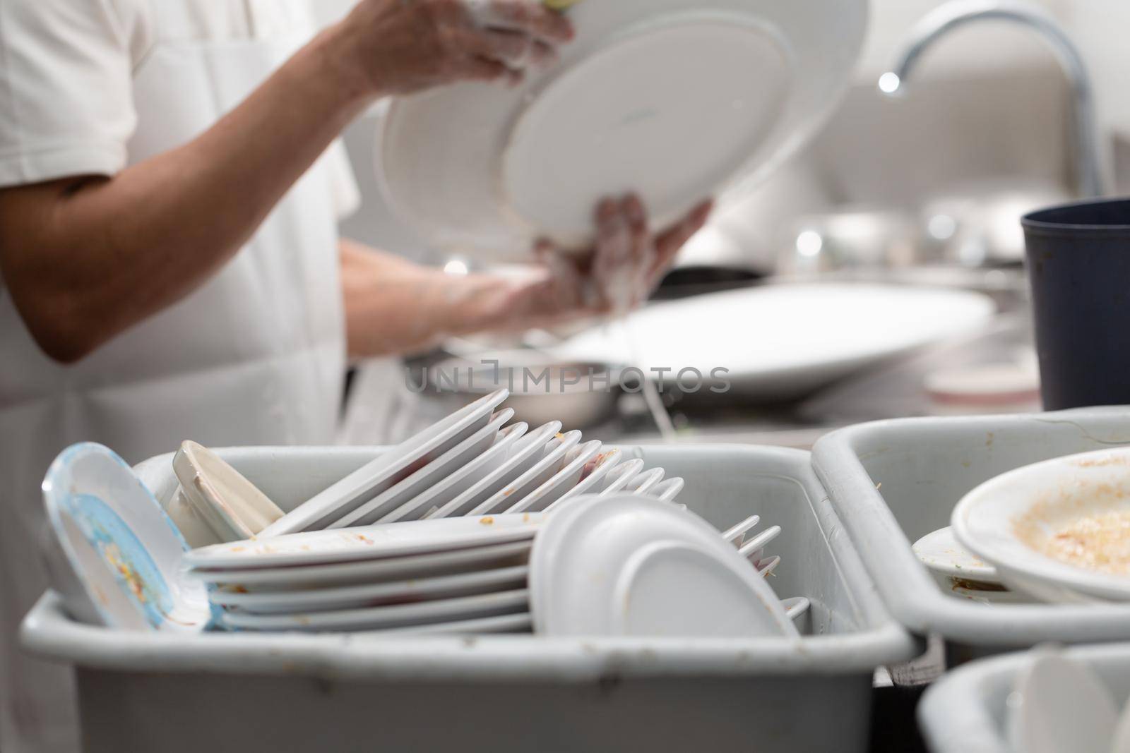 Man washing dish on sink at restaurant