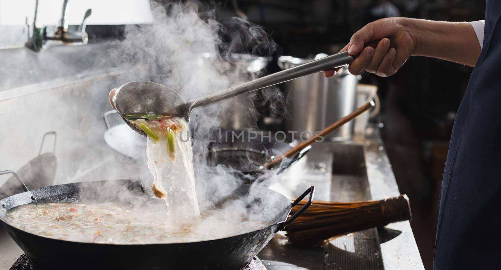 Chef cooking soup in kitchen.