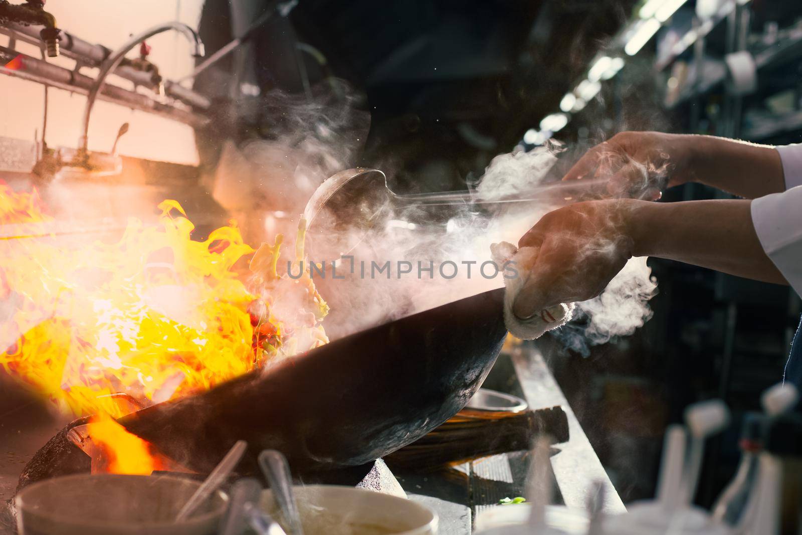 Chef stir fry busy cooking in kitchen. Chef stir fry the food in a frying pan, smoke and splatter the sauce in the kitchen.