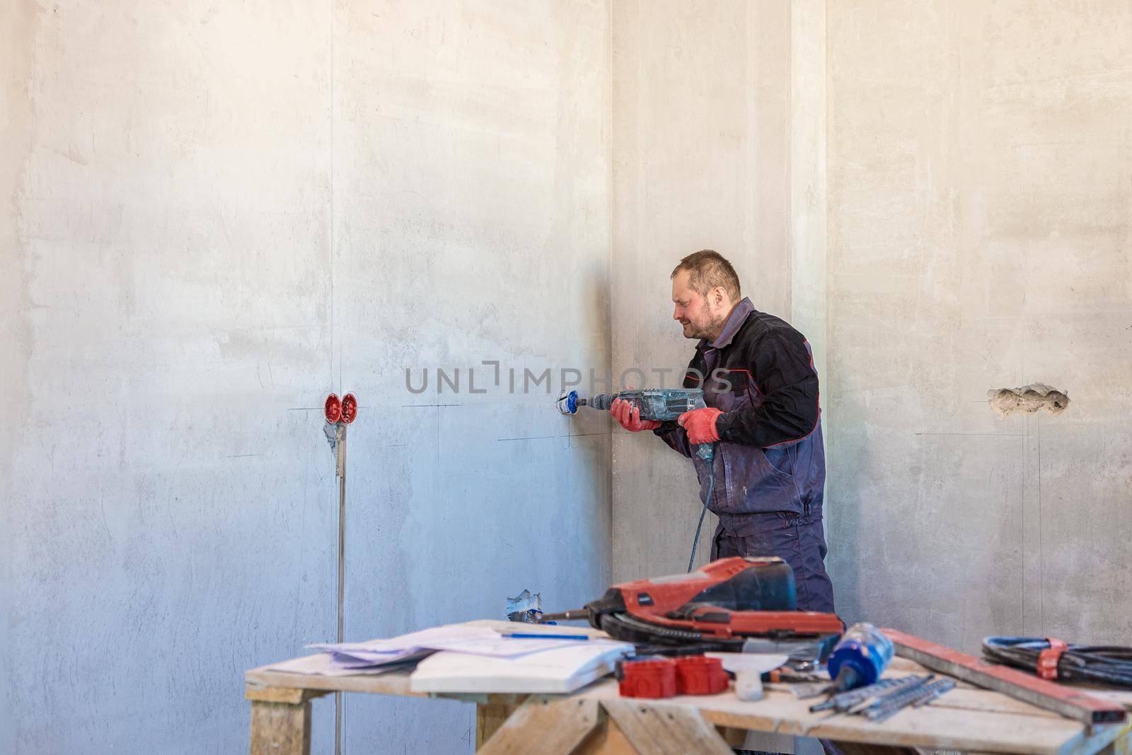 An electrician drills holes for sockets with a diamond core bit. Close-up