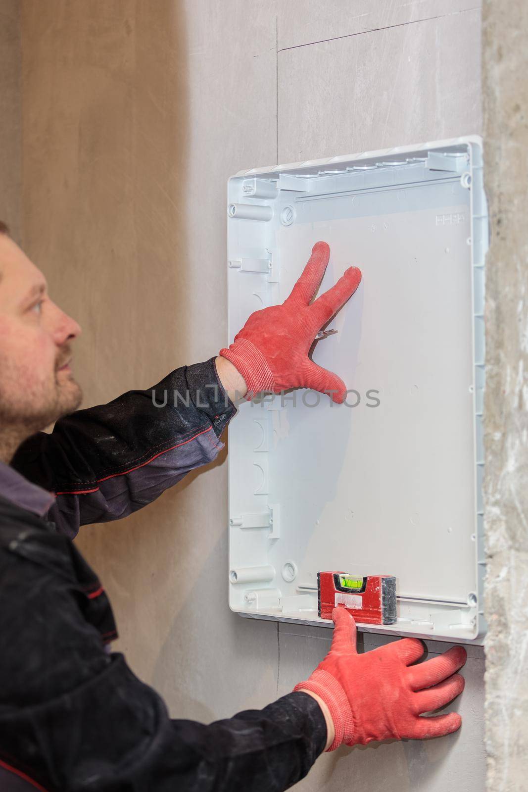 The electrician tries on and marks the lines of the electrical panel. Repair of apartments. Close-up