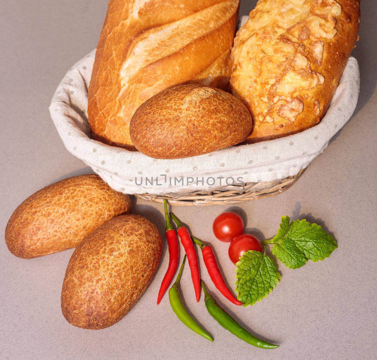 Fresh bread in a basket on the table with red peppers and tomatoes. Close-up