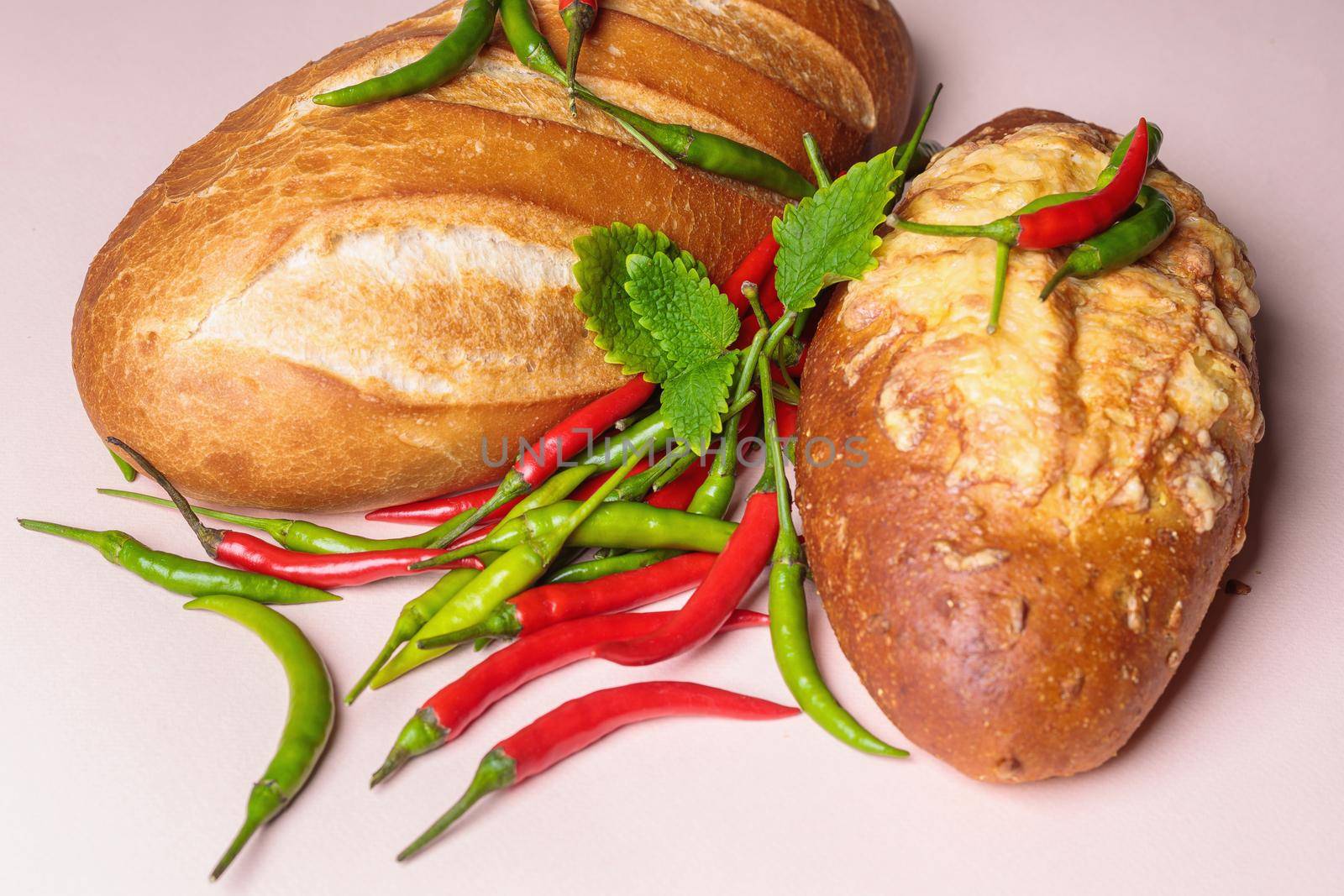 Fresh bread on the table with red and green chili peppers. Close-up