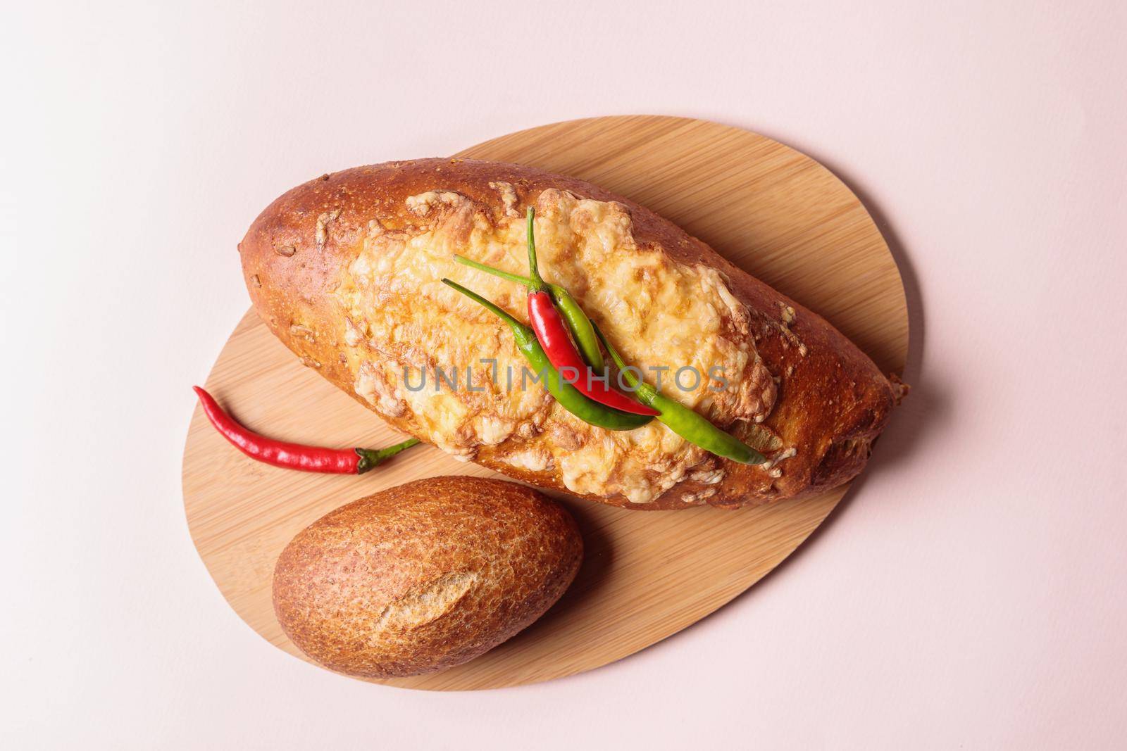 Fresh bread on a cutting board with red and green chili peppers. Close-up