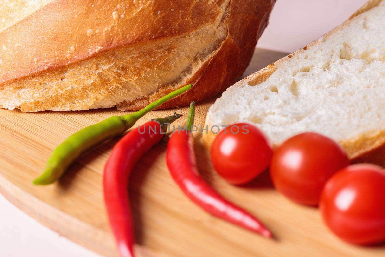 Sliced pieces of white bread with red peppers and tomatoes on a cutting board by Yurich32