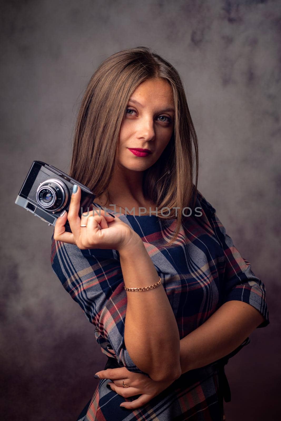 Portrait of a beautiful girl with a camera in her hands, half-length studio portrait on a gray background by Madhourse