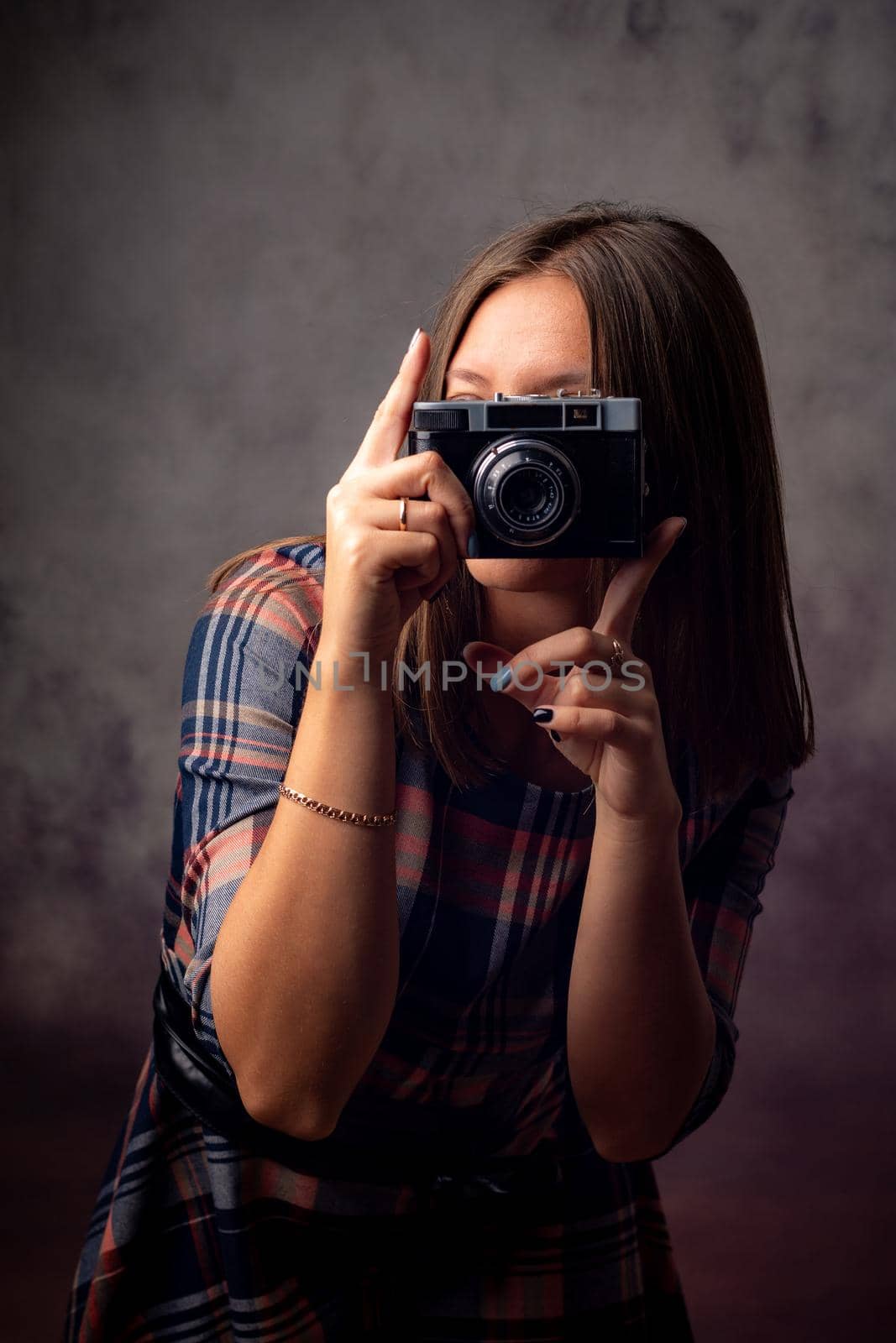 Girl photographer takes pictures with a retro camera, half-length studio portrait on a gray background by Madhourse