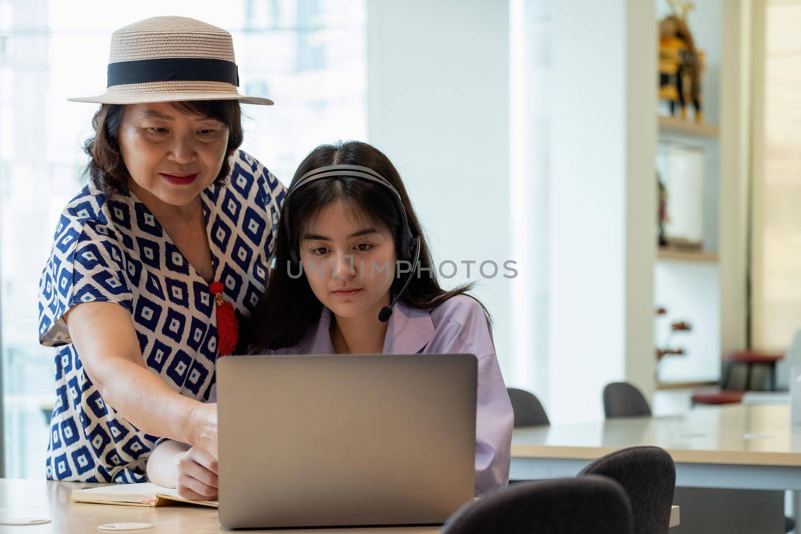 Asian mother with computer notebook teaching daughter to learn or study online at home, Homeschooling online concept. by nateemee