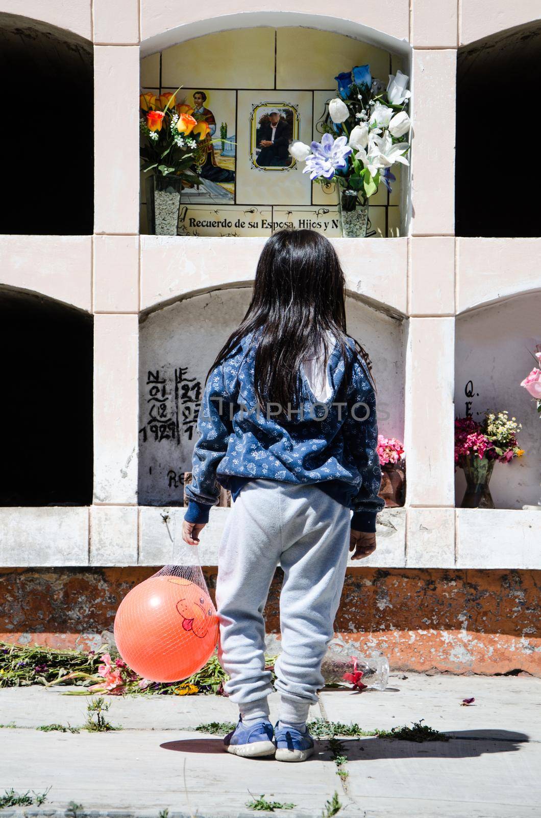 Girl on her back looking at the grave of a loved one in the cemetery of Canta - Lima - Peru