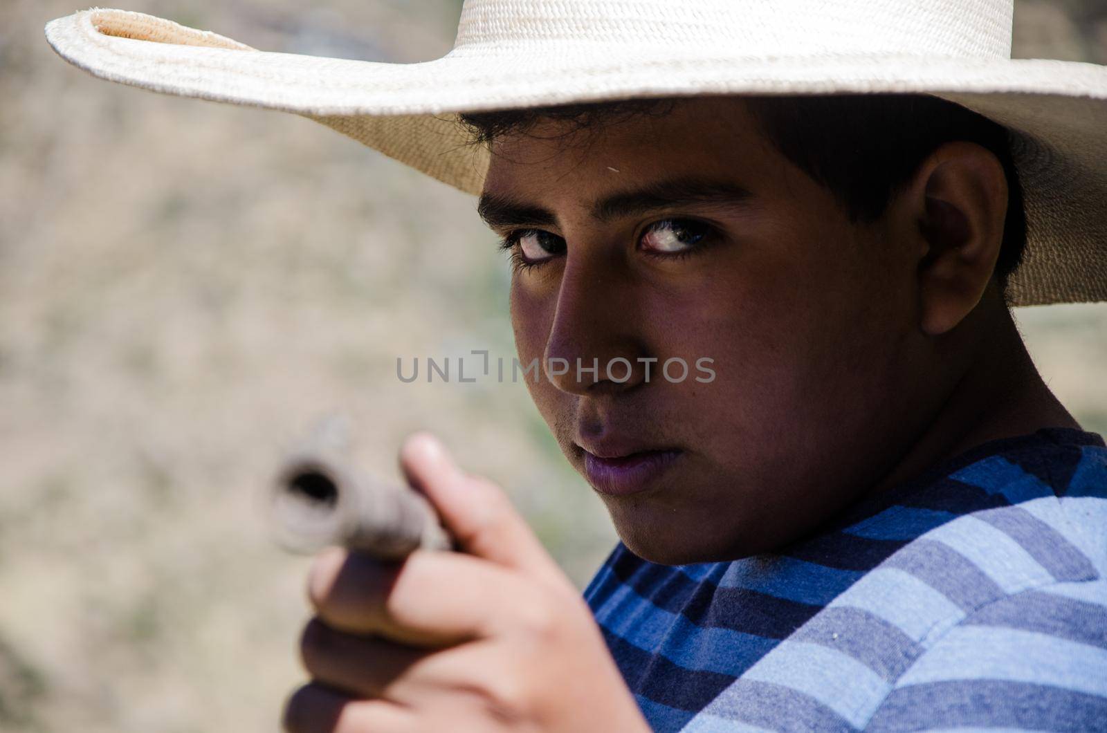 Close up face of boy with hat pointing with a rifle