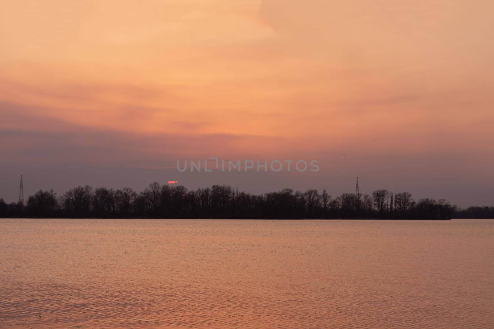 Evening sunset on a river. Early spring landscape. Ripples on the water. Dnipro River, Ukraine.
