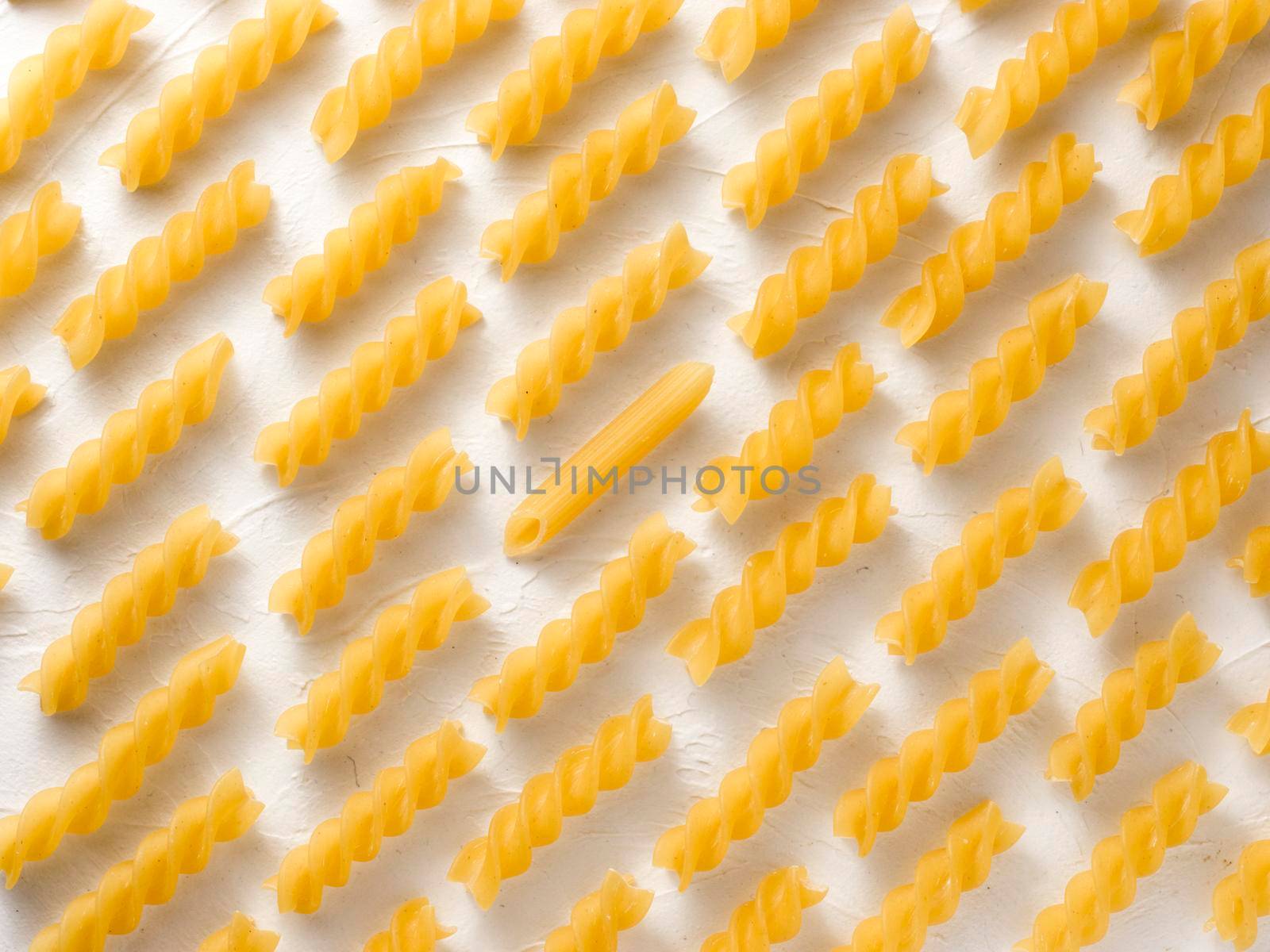 Different thinking concept. Leadership, uniqueness, independence, initiative, dissent, think different, success concept. Raw pasta fusilli and one penne pasta. Food individuality and difference