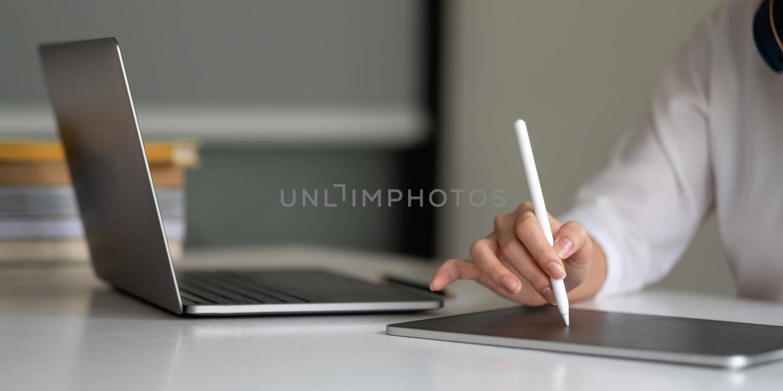 Close up hand of woman with stylus pen writing on digital notepad, touching on digital tablet screen working on laptop computer in office. Web designer working his project