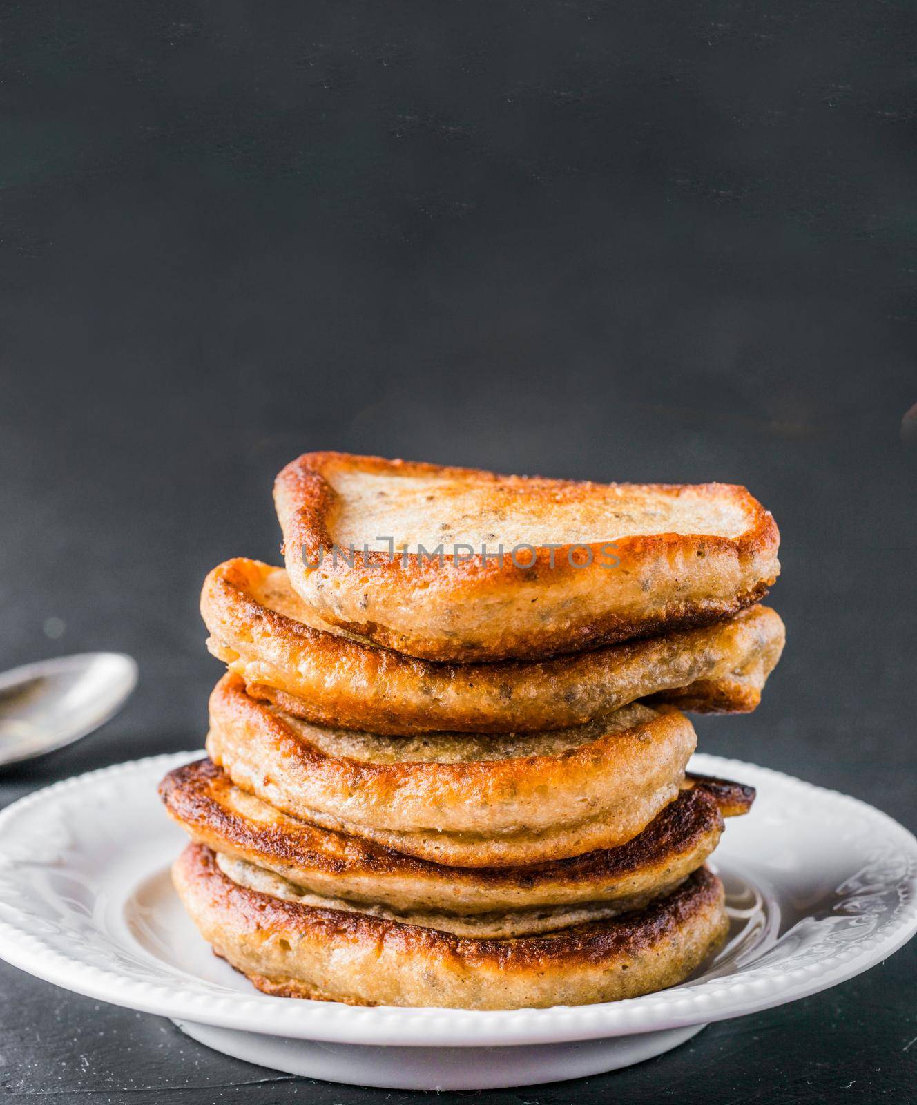 Stack of small pancakes with banana and chia seeds on black background. Pancake with chia or poppy seeds, without eggs. Eggless concept. Copy space