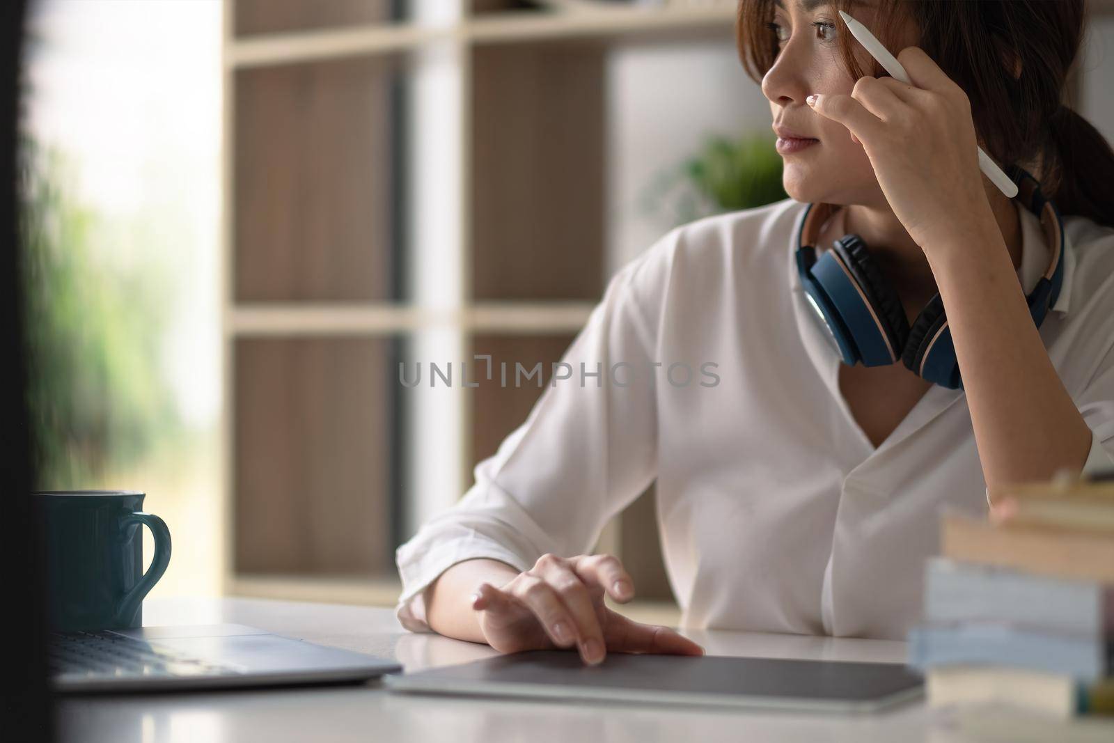 Shot of graphic designer drawing on digital tablet on wooden worktable at home.