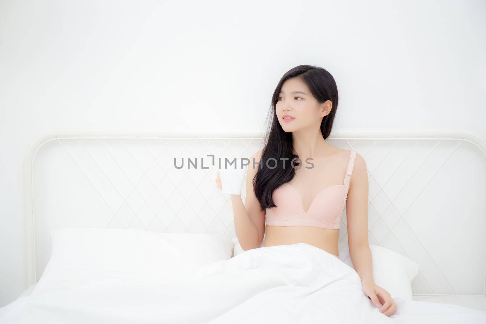 Beautiful young asian sexy woman in underwear drinking coffee in the morning on bed at bedroom, asia girl with seductive figure fit drinking beverage for relax after wake up, lifestyle concept.