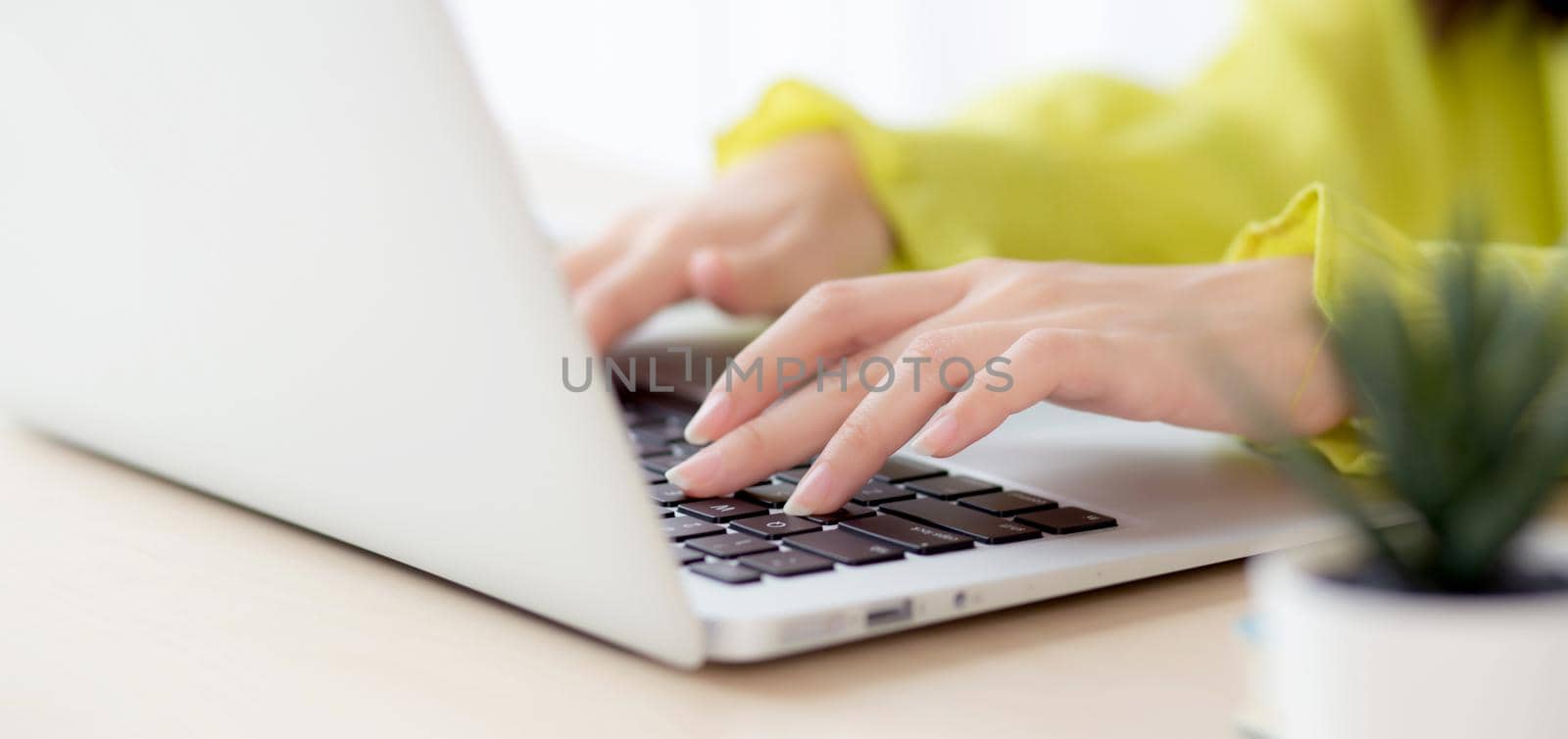 Closeup of hand young asian businesswoman working on laptop computer on desk at home office, freelance looking and typing on notebook on table, woman studying online, business and education concept.