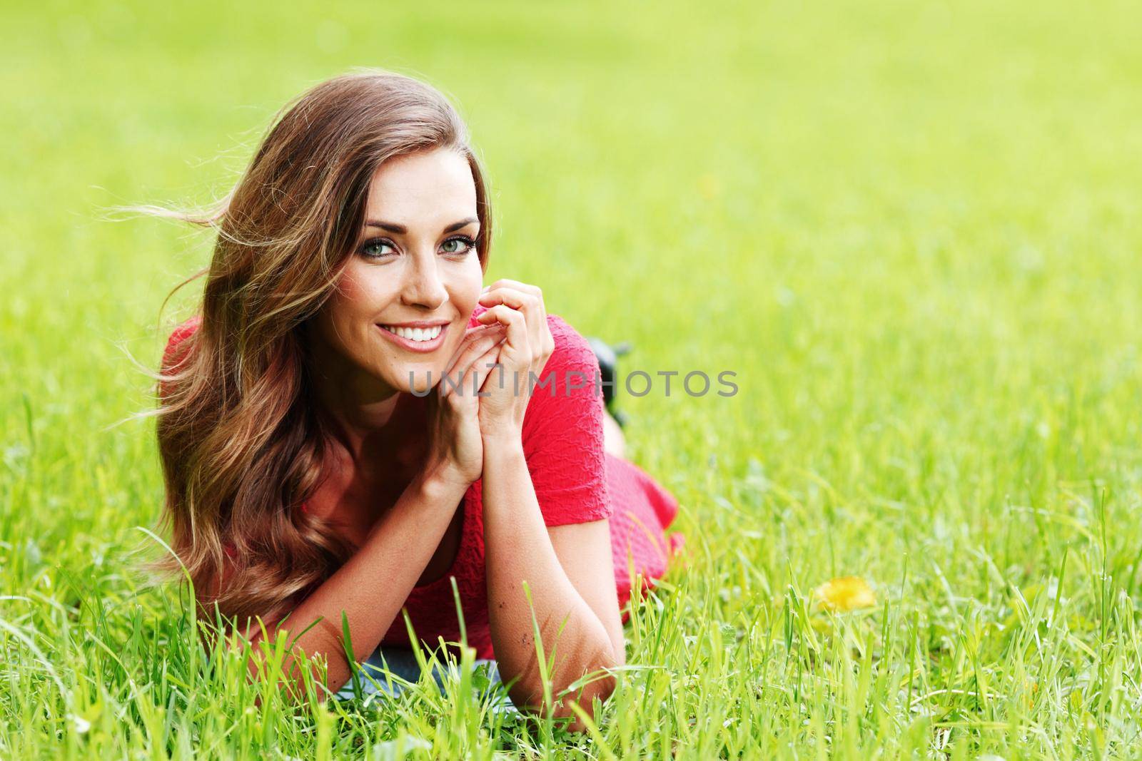 Smiling woman laying on spring green grass and smiling