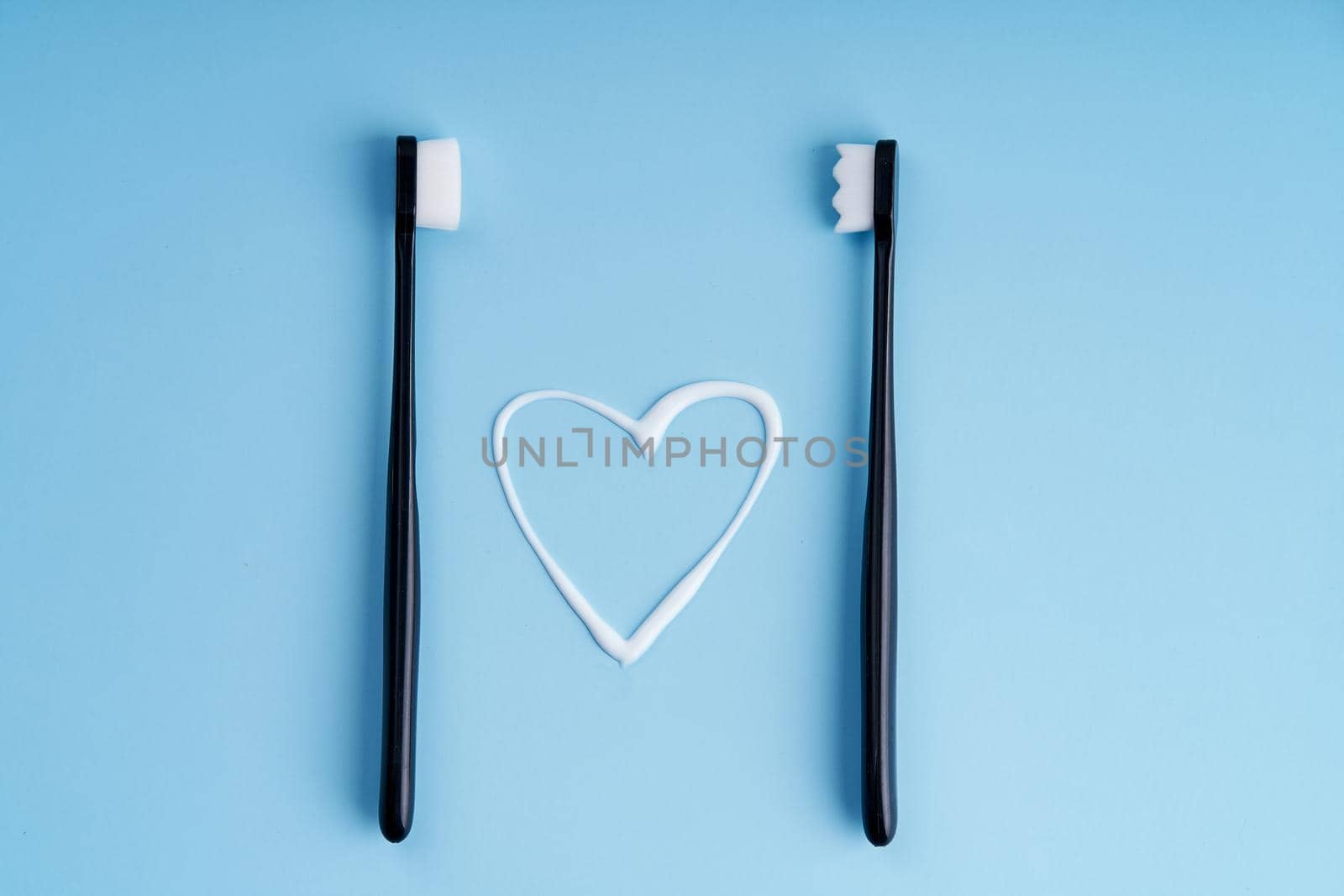 Heart shaped toothpaste between two toothbrushes close up by Try_my_best