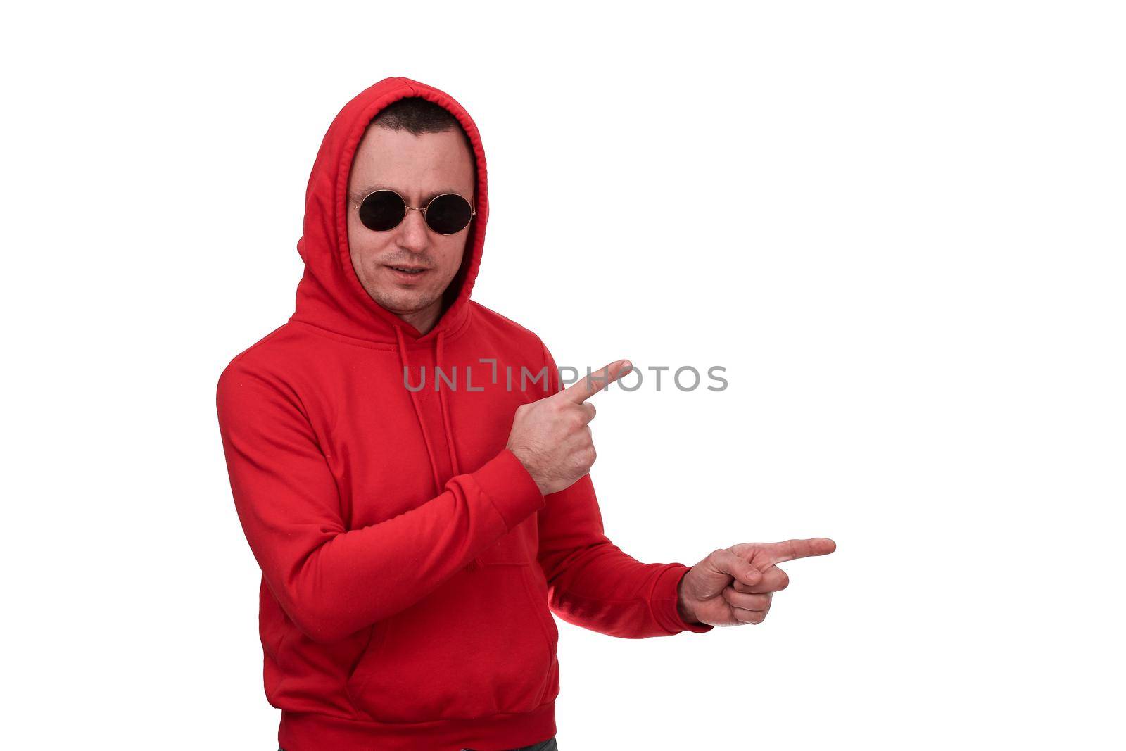 A man in a red hooded sweatshirt and black glasses points to an empty space. Isolated on a white background.