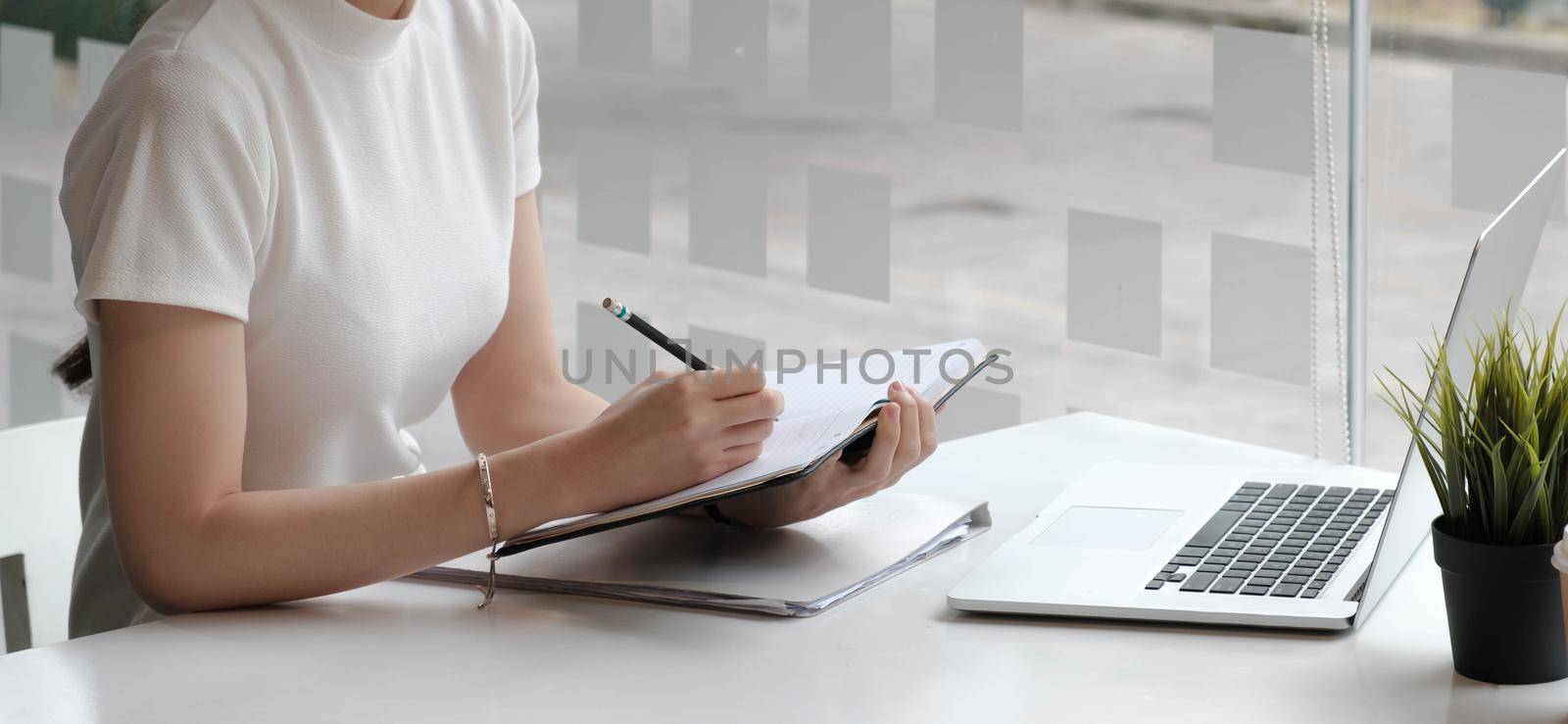 woman reading agreement paper before sign document with use pen and laptop at work. by wichayada