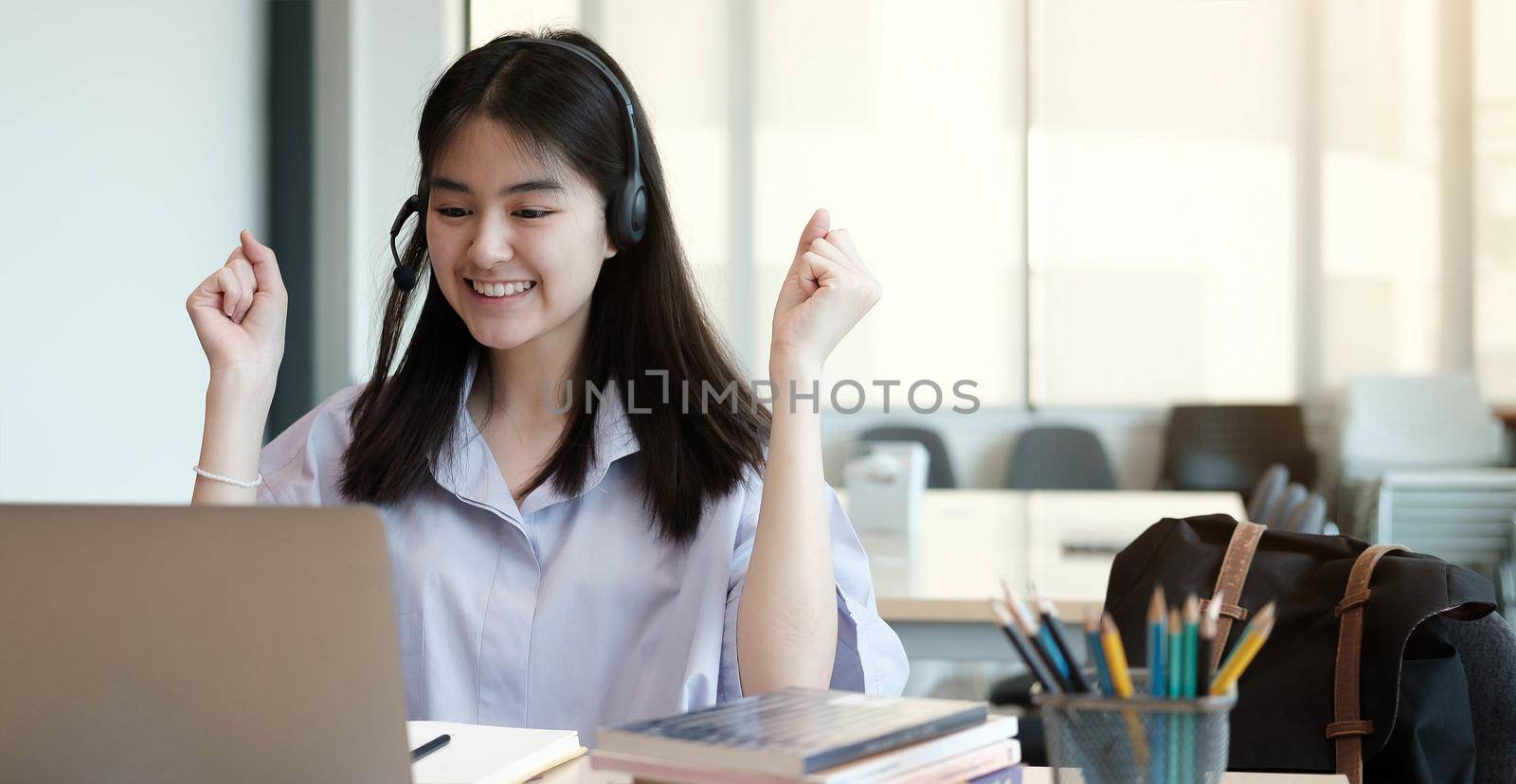 Young girl showed hands successful to her friends on a video call on laptop in the home. She’s happiness to learning lessons online. Protect coronavirus or COVID-19. Education from home.
