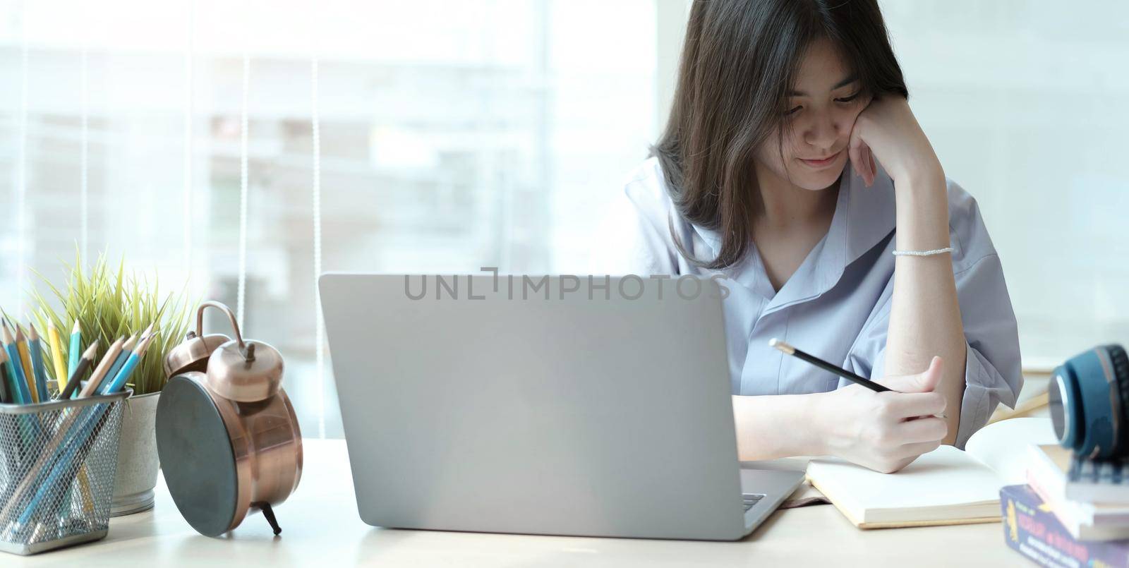 attractive woman writing in notepad while watching webinar on laptop in chome by wichayada