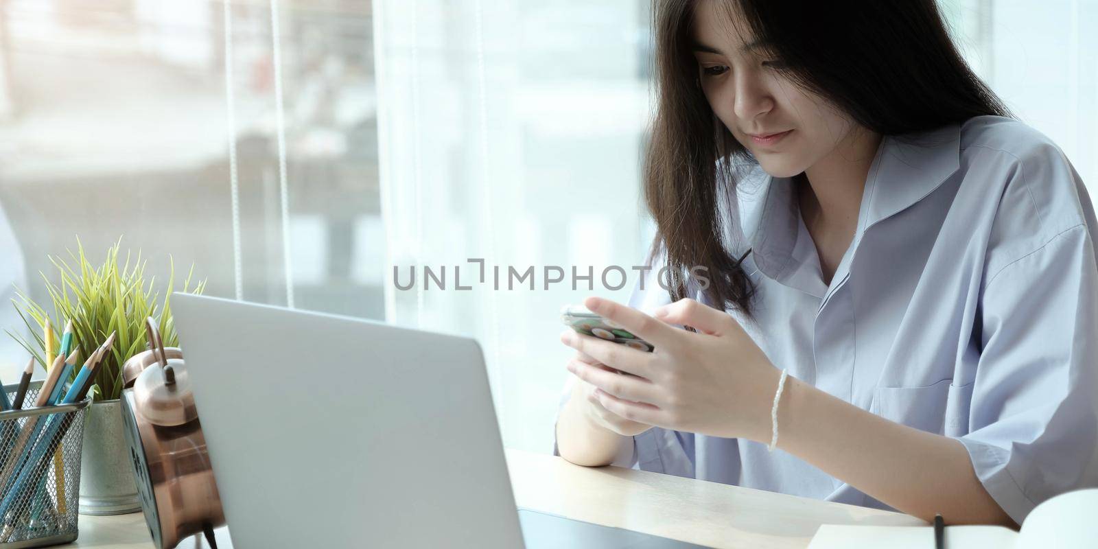 Portrait of woman using smartphone and smiling by wichayada