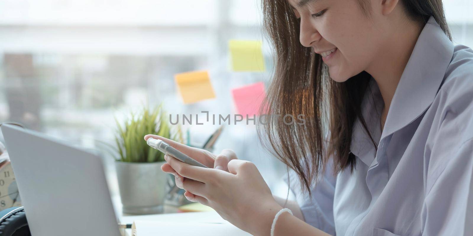 girl school student hold smartphone using distance learning mobile app online watching video course or zoom calling making notes in workbook sit at home.
