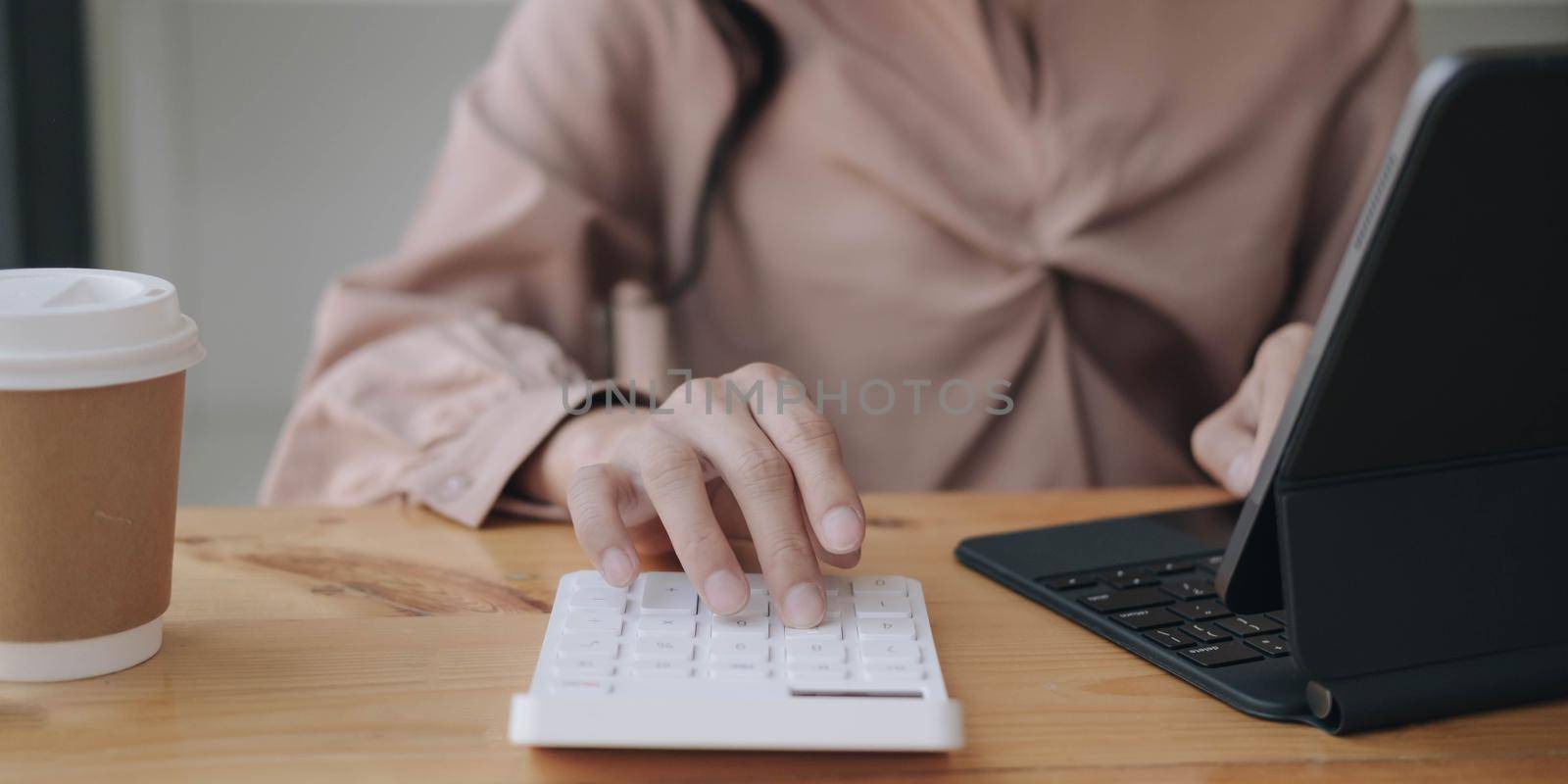 Business woman working in finance and accounting Analyze financial budget with calculator and laptop computer in the office by wichayada