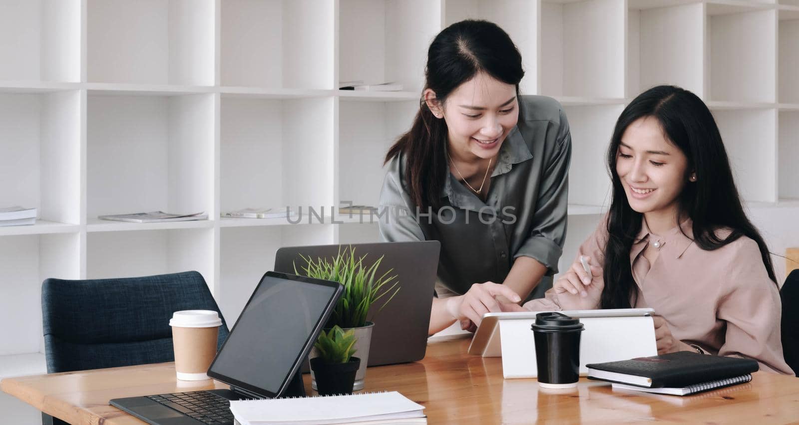 Two young business woman working with modern devices and discussing for new project investments.
