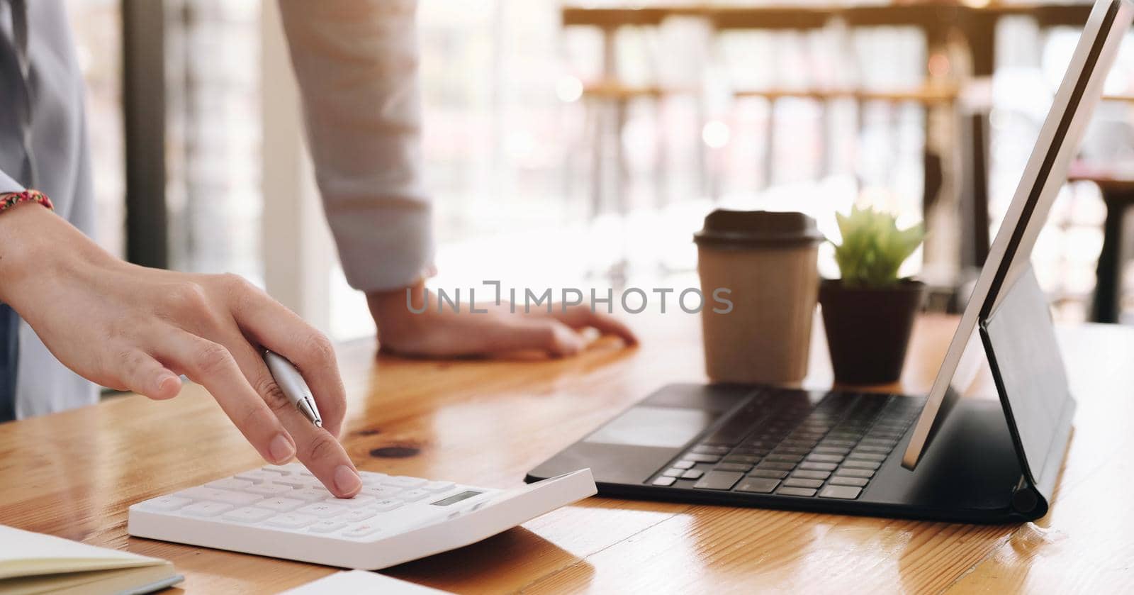 Asian woman pressing calculate for prepare information of report to correct. Still holding a paper work of laptop. by wichayada