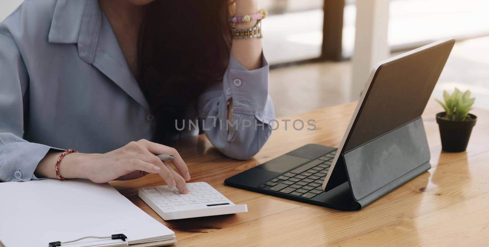 Business woman using calculator for do math finance on wooden desk in office and business working background, tax, accounting, statistics and analytic research concept

